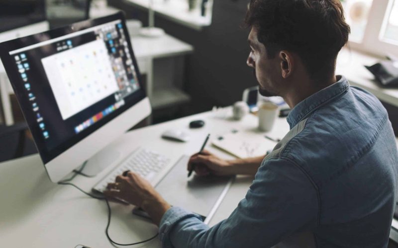 Modern designer sitting in front of computer and working in office